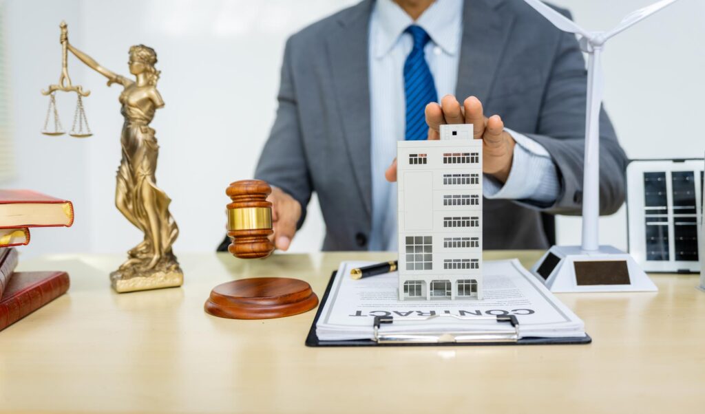 Lawyer from All West Law Group holds a gavel and a model house on a desk, symbolizing legal representation in real estate.