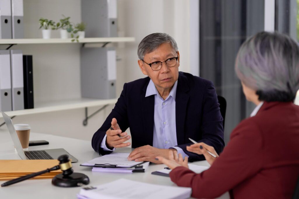 A man and woman seated at a table, discussing matters related to All West Law Group.
