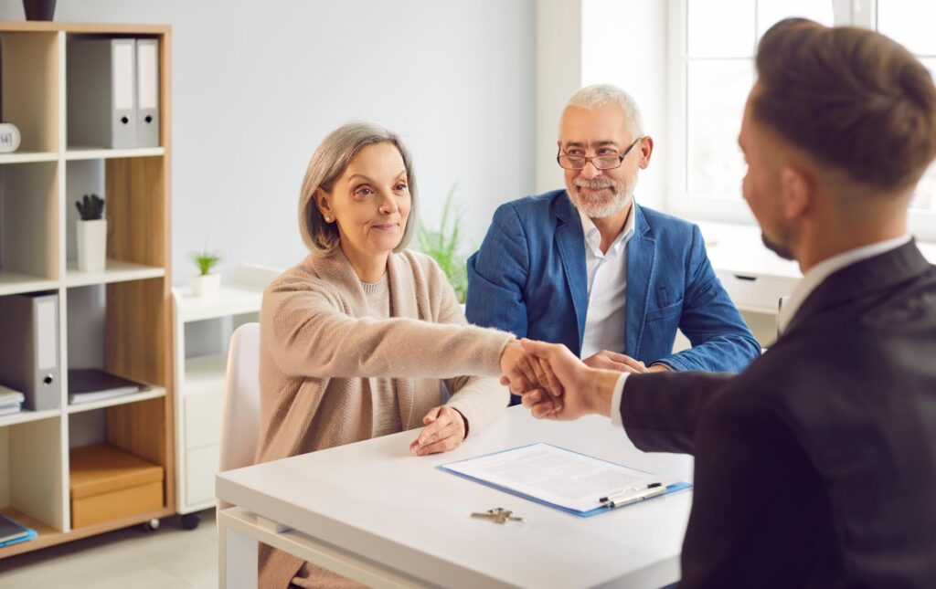 Senior couple and realtor handshake deal in office. Helping clients buy, rent home, apartment,