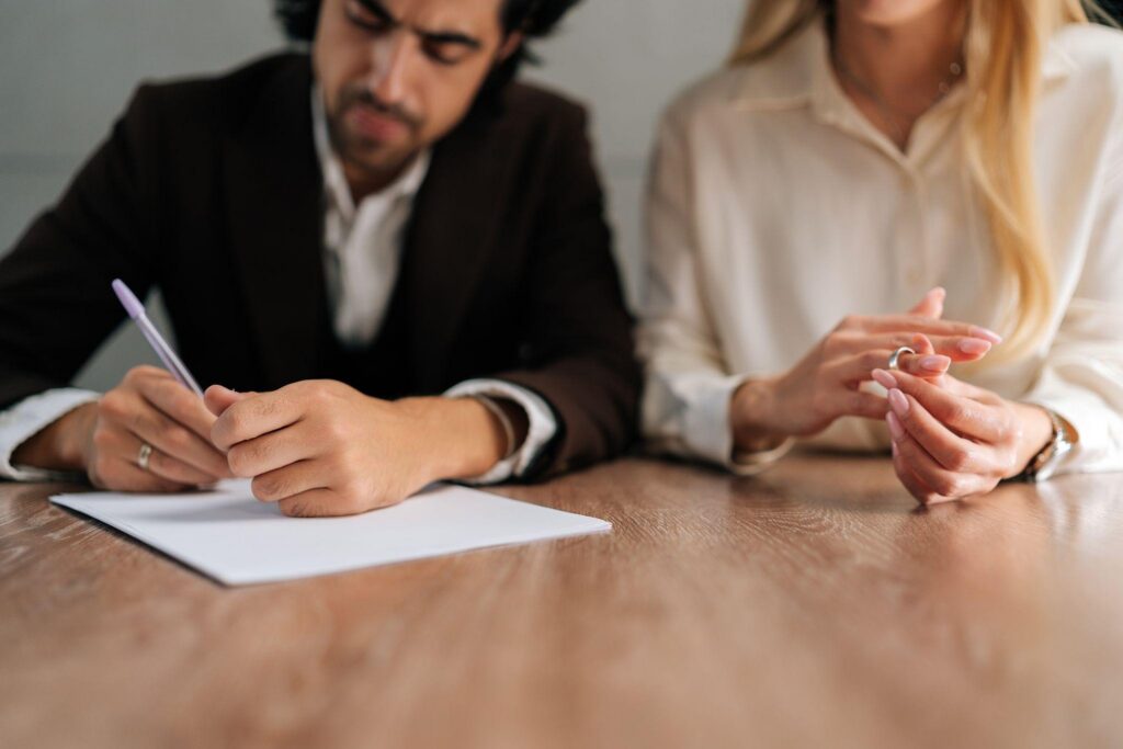 A man and woman at a table engaged in signing a contract together