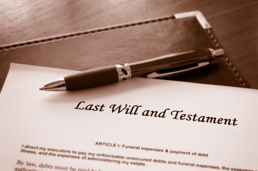 A close-up shot of a Last Will and Testament document with a pen resting across it on a leather folder.