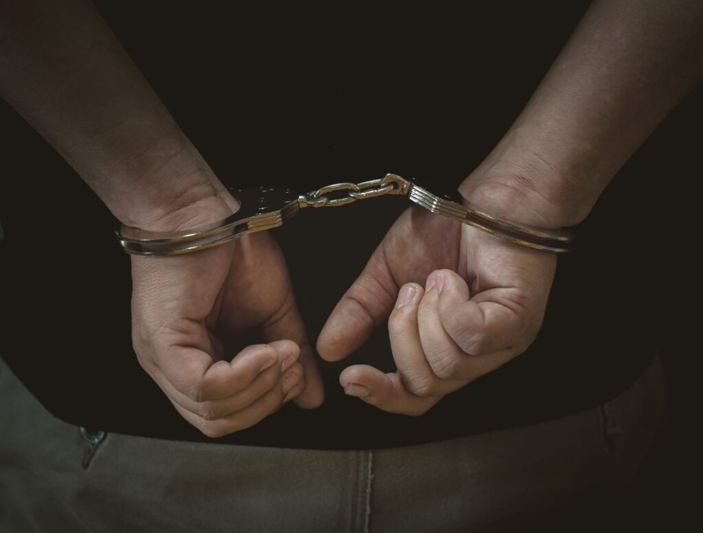 A close-up view of a person's hands handcuffed behind their back.