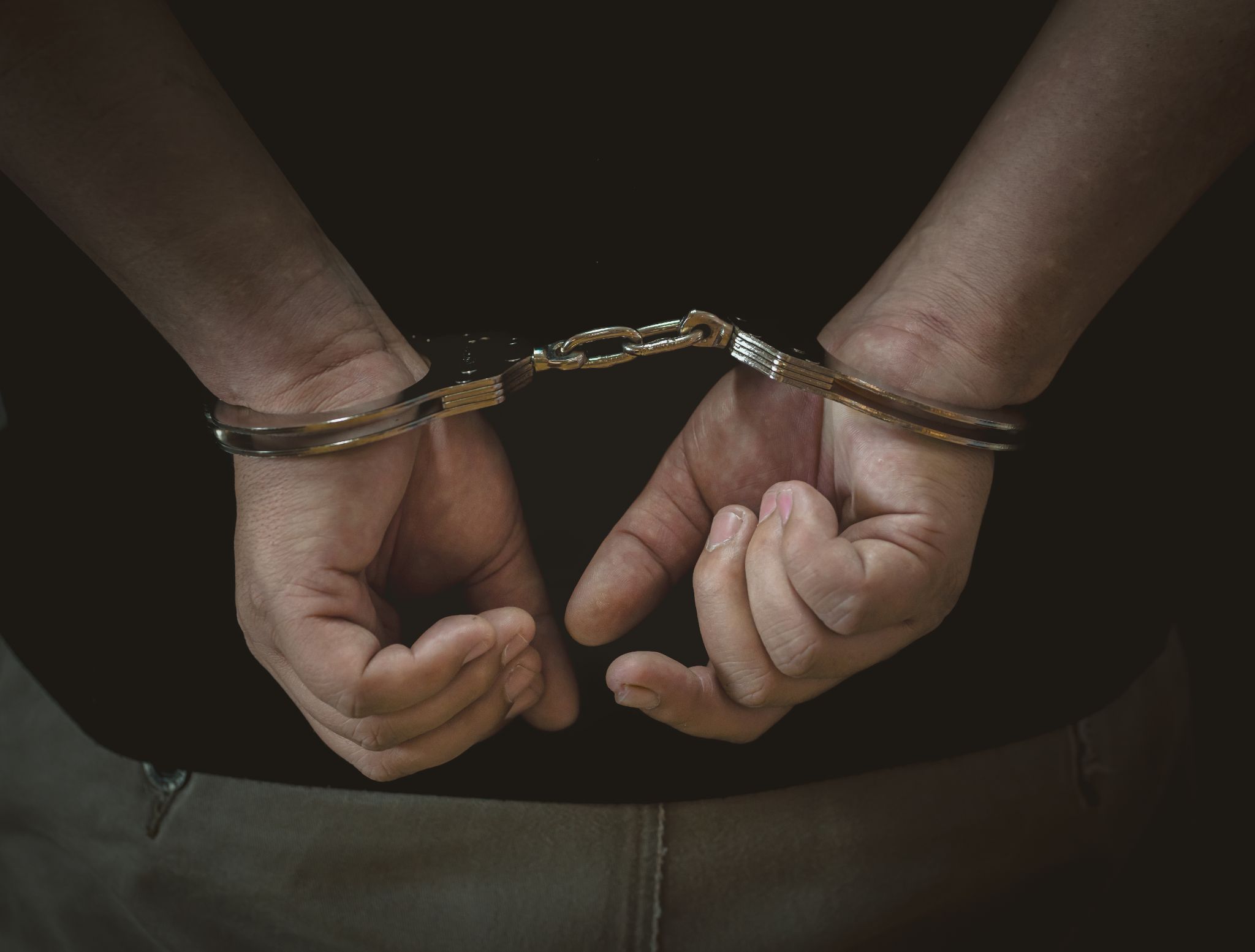 A close-up view of a person's hands handcuffed behind their back.