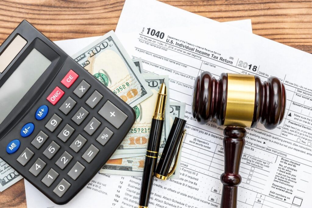 A tax return calculator gavel and cash on a wooden table represent legal and financial matters