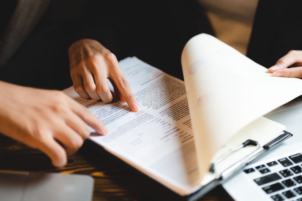 Close-up of hands pointing to specific clauses on printed documents attached to a clipboard.