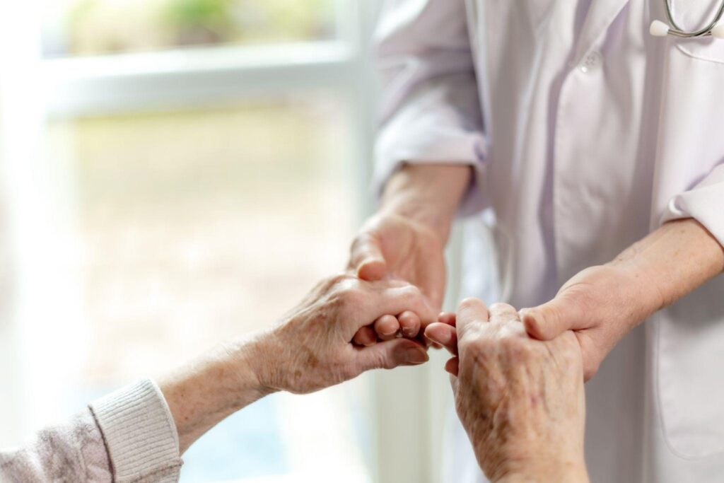 Close up of a doctor gently holding an elderly patient hands